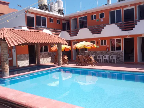 Alberca de Hotel Valeria con palapa y sillas alrededor de las habitaciones