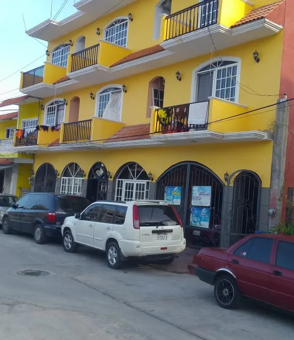 Fachada de Hotel El Pariente, edificio de tres pisos color amarillo con balcones
