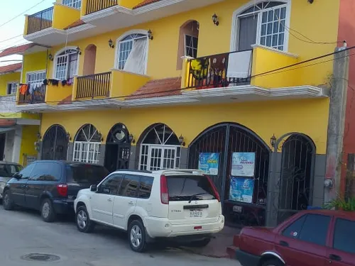 Fachada de Hotel El Pariente, edificio de tres pisos color amarillo con balcones