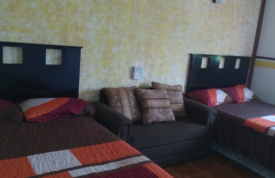 Habitación de Hotel El Pariente con dos camas y sillón