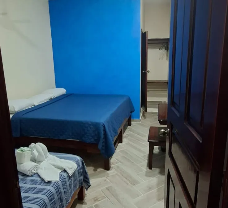 Habitación de Casa Llanos en Tecolutla con pared azul y dos camas matrimoniales