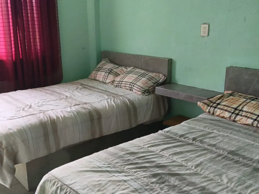 Habitación doble con dos camas matrimoniales y cabeceras grises en Quinta Ruben's