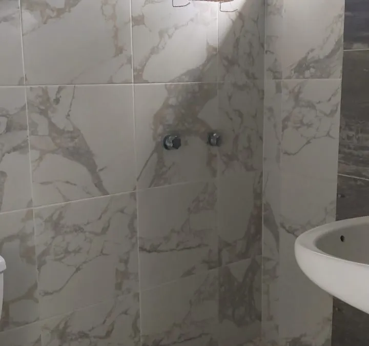 Baño privado con regadera tipo lluvia y muros de mármol en Quinta Ruben's