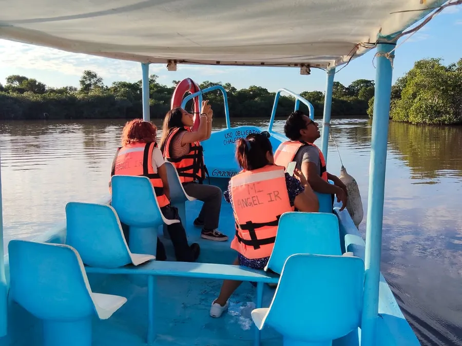 Turistas con chalecos salvavidas marcados "Mi Ángel IR" navegando por el estero