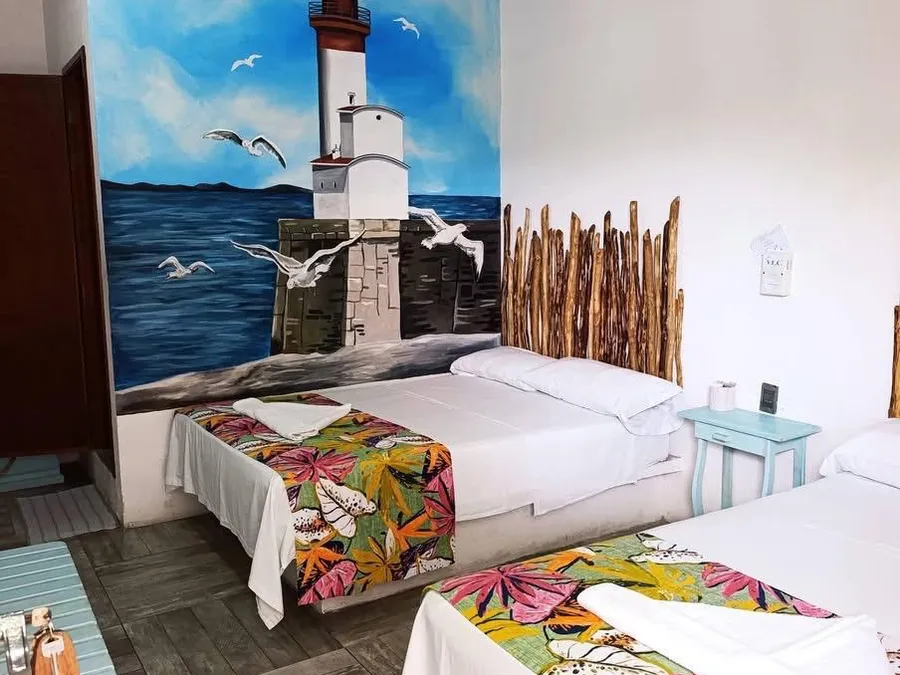 Habitación con mural de faro y colchas florales de Hotel Nautilus en Tecolutla