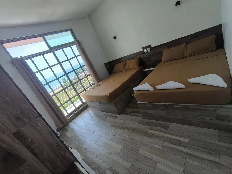 Habitación del Hotel LunAzul con camas matrimoniales y ventanal al exterior