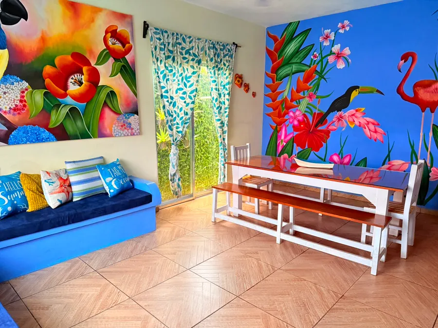 Sala con mural de flamencos y tucán de Casa Vía Mar en Tecolutla