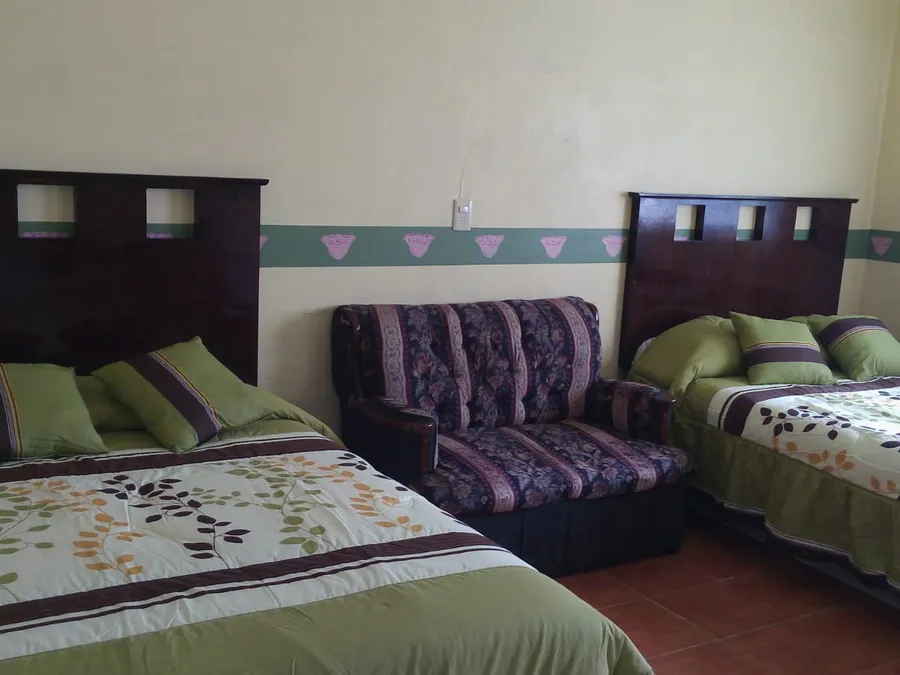 Habitación de Hotel El Pariente con dos camas dobles