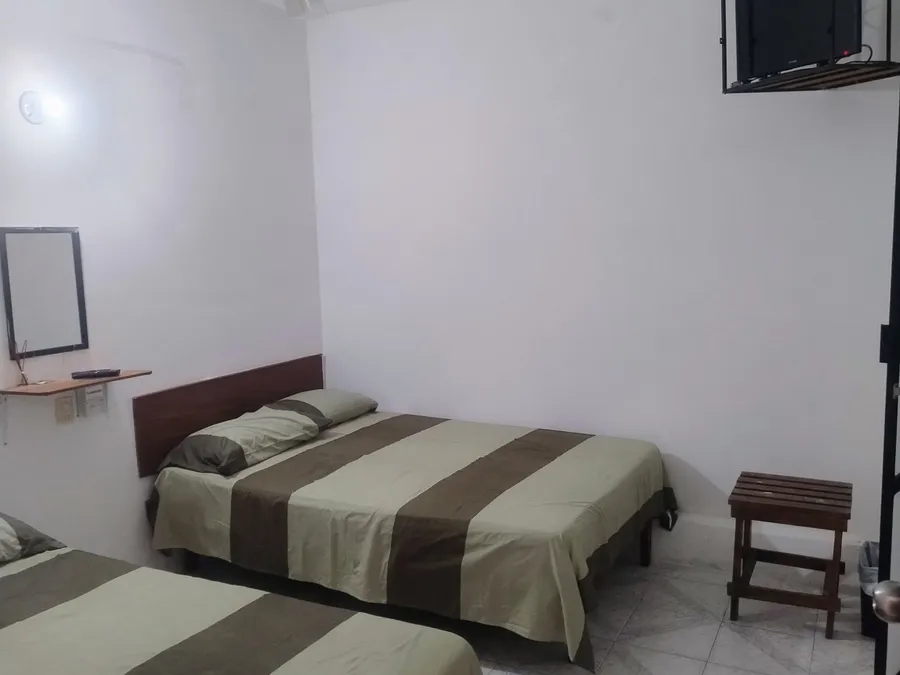 Habitación de Habitaciones Mary con dos camas matrimoniales, ventilador de techo y televisión