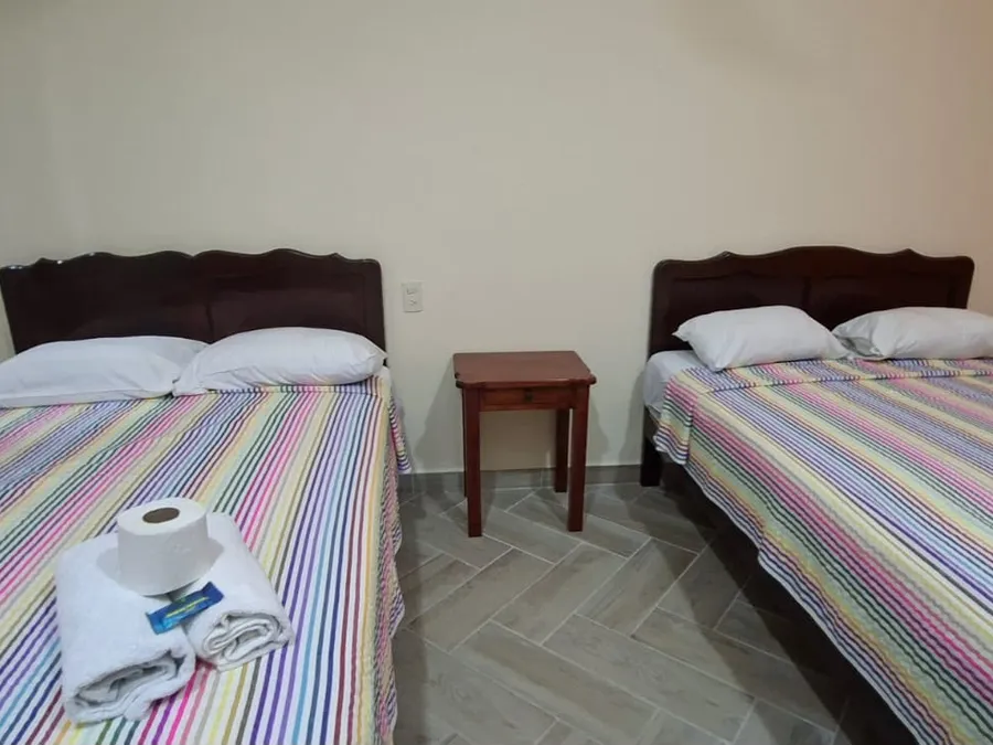 Habitación de Casa Llanos en Tecolutla con dos camas matrimoniales y buró