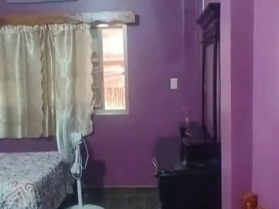 Vista general de la habitación con cama, ventilador y mueble de madera
