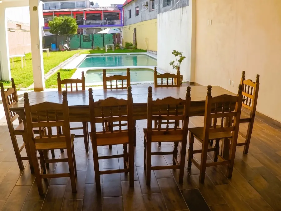 Comedor techado de Casa Xanath con mesa de madera para 10 personas frente a la alberca