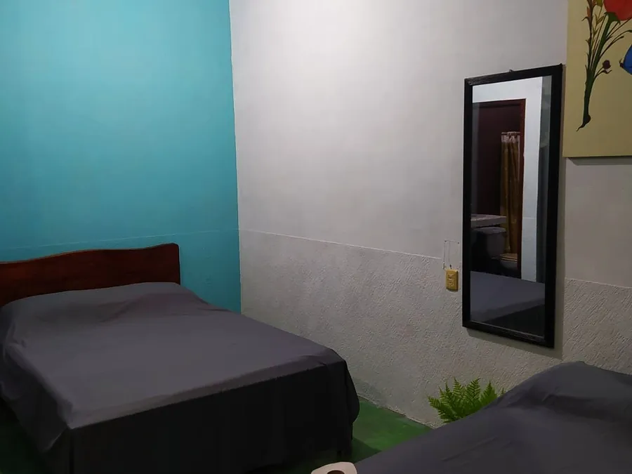 Recámara de Casa Mandala con dos camas, espejo de cuerpo entero y pared celeste
