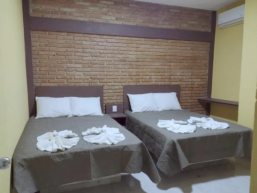 Recámara de Casa Xanath con dos camas, muro de ladrillo y aire acondicionado
